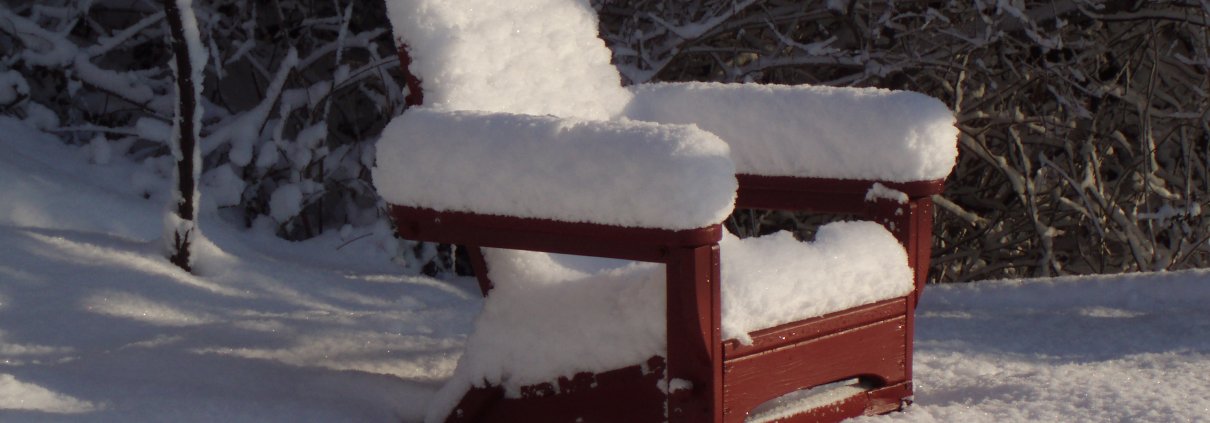 Red Adirondack chair covered in snow